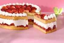 Gâteau aux fraises partiellement tranché — Photo de stock