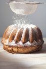 Closeup view of sprinkling Gugelhupf with icing sugar — Stock Photo