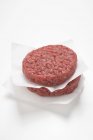 Raw burgers on papers — Stock Photo