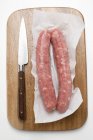 Saucisses sur papier sur planche à découper — Photo de stock