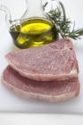Chuletas de cerdo crudas con aceite de oliva - foto de stock