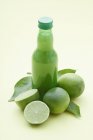 Bottle of lime juice and fresh limes — Stock Photo