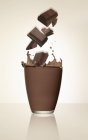 Primo piano vista di pezzi di cioccolato che cadono a vetro di cacao — Foto stock