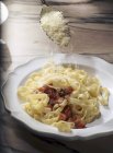 Sprinkling Parmesan on tagliatelle pasta — Stock Photo