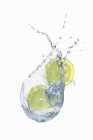 Éclaboussure d'eau avec des tranches de citron — Photo de stock