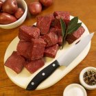 Cubos de carne crua na placa de corte — Fotografia de Stock