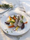 Veal on a bed of vegetables with a wine sauce on white plate — Stock Photo