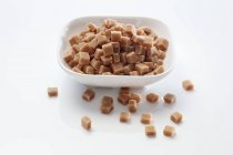 Closeup view of caramel cubes in white bowl — Stock Photo