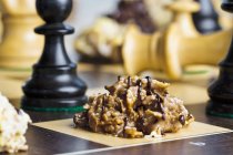 Nahaufnahme von Nuss-Krokant mit Schokolade überträufelt auf Schachbrett — Stockfoto