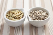Pumpkin and sunflower seeds in bowls — Stock Photo