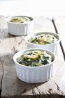 Oven-baked spinach frittata in white pots on wooden surface — Stock Photo