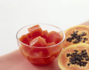 Vue rapprochée de morceaux de papaye en conserve dans un bol et la papaye fraîche coupée en deux — Photo de stock