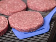 Raw burgers on electric grill — Stock Photo