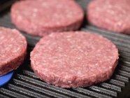 Raw burgers on electric grill — Stock Photo