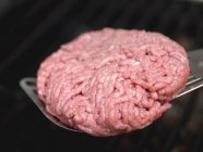 Placer le hamburger sur le support de barbecue — Photo de stock