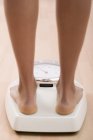 Обрезанный вид женских ног, стоящих на весах в ванной — стоковое фото