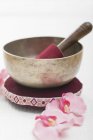 Closeup view of a singing bowl on pillow near pink orchids — Stock Photo