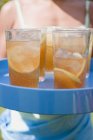 Vista da vicino del tè freddo in bicchieri su vassoio con donna sullo sfondo — Foto stock