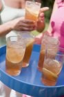 Closeup view of iced tea in glasses on tray with women on background — Stock Photo