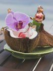 Coco abierto con menta y orquídea - foto de stock