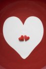 Vista de cerca de los corazones de azúcar roja en el corazón blanco - foto de stock