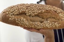 Жінка тримає буханку вівсяного хліба — стокове фото