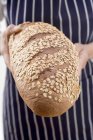 Woman holding loaf of oat bread — Stock Photo