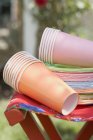 Colored paper cups and plates on folding stool — Stock Photo