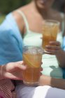 Vue de jour de deux femmes tenant des verres de thé glacé — Photo de stock