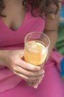 Closeup view of woman holding a glass of iced tea with lemon — Stock Photo