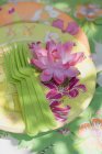 Elevated view of water lily on floral patterned paper plates and green plastic forks — Stock Photo