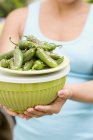 Woman holding grilled chillies on top of a green bowl in hands, midsection — Stock Photo
