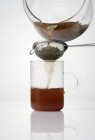 Soulager le thé à travers une passoire — Photo de stock