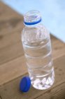 Vue rapprochée d'une bouteille d'eau ouverte près de la piscine — Photo de stock