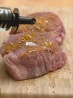 Sprinkling seasoned beef medallions with oil — Stock Photo