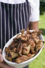 Man holding grilled chicken wings — Stock Photo