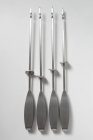 Top view of four barbecue skewers on white surface — Stock Photo