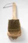 Vista close-up de uma escova de arame na superfície branca — Fotografia de Stock