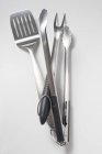 Closeup view of tongs with carving fork and spatula on white surface — Stock Photo