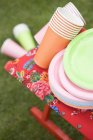 Tazas y platos de papel de colores en taburete plegable - foto de stock