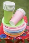 Colored paper cups and plates on folding stool in garden — Stock Photo