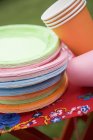 Tasses et assiettes en papier coloré sur tabouret pliant dans le jardin — Photo de stock