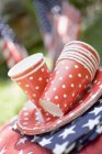 Tasses et assiettes en papier empilées colorées sur les drapeaux américains dans le jardin — Photo de stock