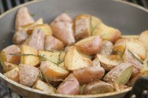 Жареный картофель с розмарином в сковороде — стоковое фото
