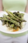 Woman holding plate of grilled asparagus — Stock Photo
