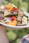 Hands holding a plate of grilled vegetables — Stock Photo