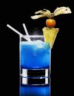 Closeup view of Blue Curacao with ice, pineapple slice, physalis and drinking straws — Stock Photo