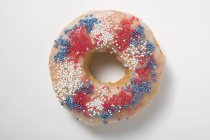Doughnut with sprinkles in red — Stock Photo