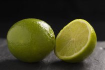 Limes fraîches entières et coupées en deux — Photo de stock