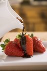 Despejar chocolate sobre morangos — Fotografia de Stock